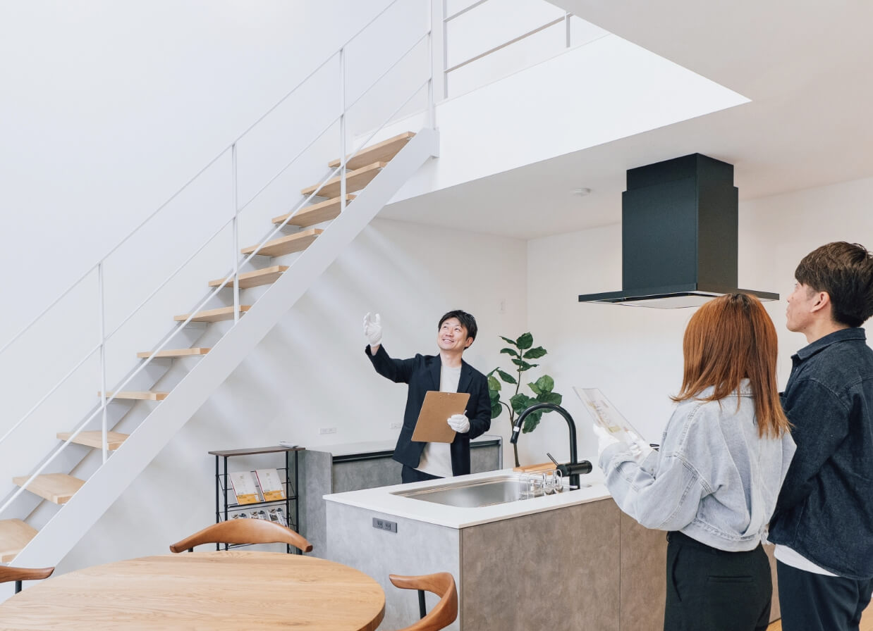 夫婦に家の作りを説明する男性スタッフ