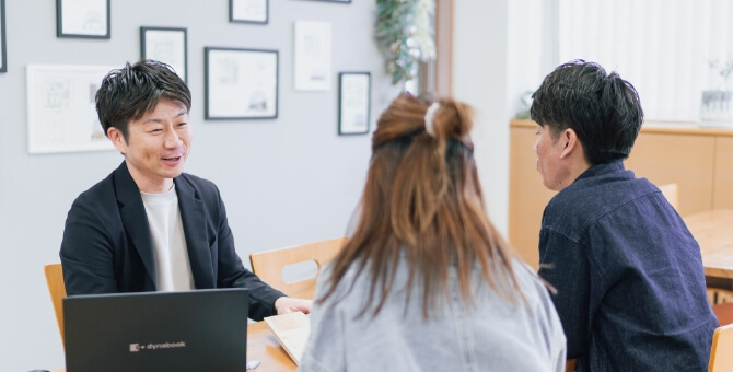 夫婦のお客さんと会話をする男性スタッフ
