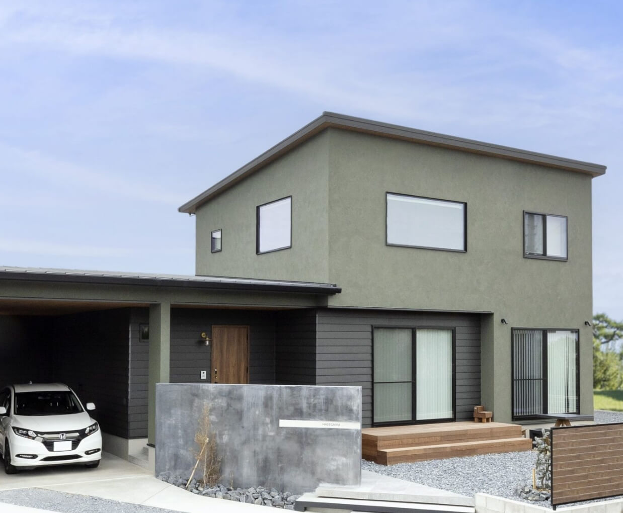 広い庭と駐車場のあるシンプルモダンな家の外観